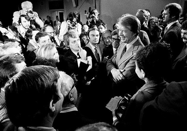 Pres. Jimmy Carter, right, is surrounded by reporters and photographers at the conclusion of his news conference in the Executive Office Building, Wednesday, March 9, 1977, Washington, D.C. He announced that the administration is lifting the ban on travel by U.N. citizens to Vietnam, North Korea, Cambodia and Cuba effective March 18.