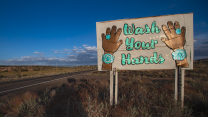 A sign featuring native Navajo turquoise jewelry reads "Wash Your Hands" for passersby on a highway 98 on the Navajo Reservation.