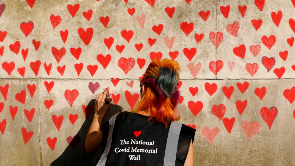 A woman draws red hearts representing individual coronavirus deaths onto the newly-unveiled National Covid Memorial Wall opposite the Houses of Parliament in London, England, on March 30, 2021.