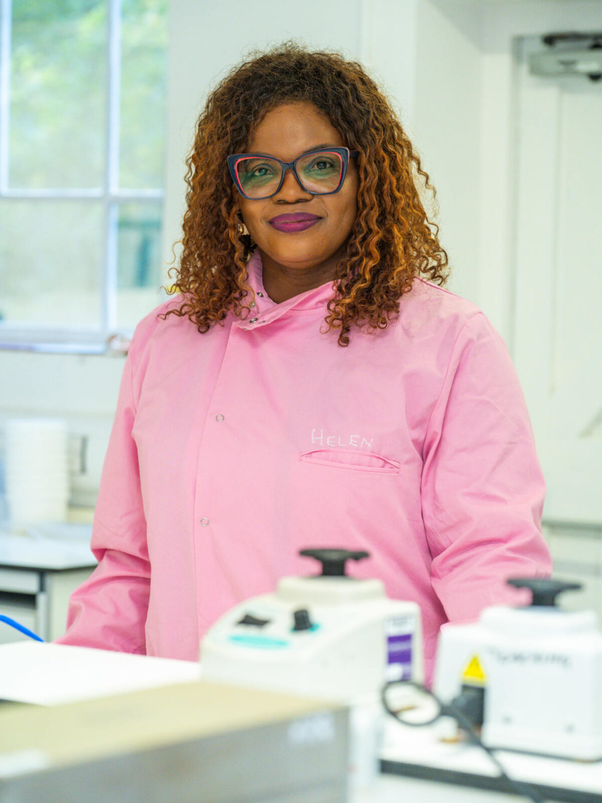 A Black woman wearing a pink lab coat.