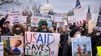 Protesters in front of the US Capitol hold signs supporting USAID