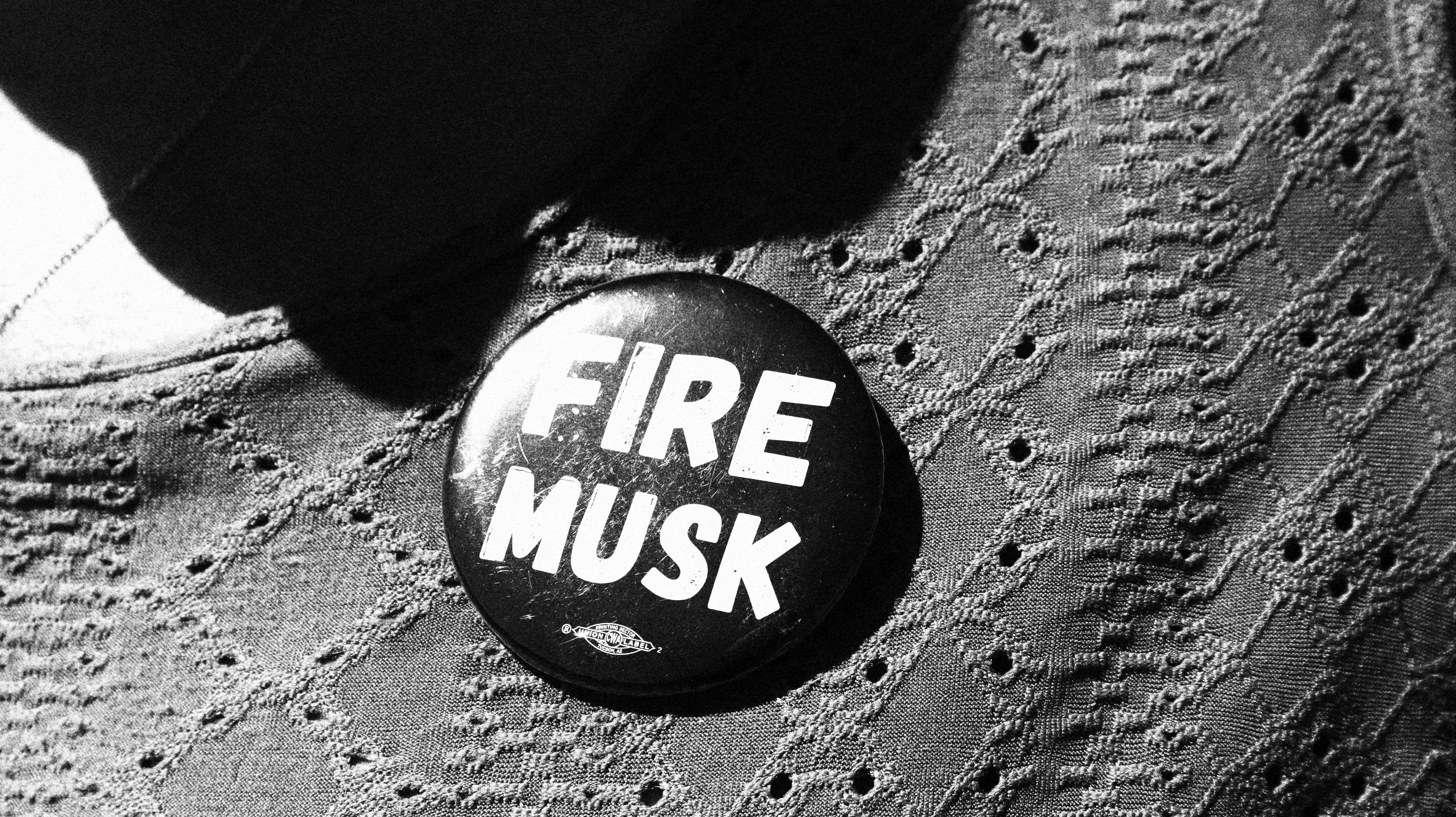 A button pinned to a person's shirt reads, "Fire Musk."