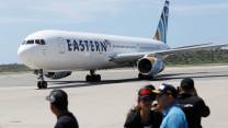 An Eastern aiilines flight on the tarmac with deported migrants in the foreground.
