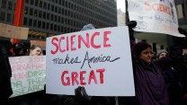 An unseen person holds a sign reading, "Science makes America great," amid a protest.