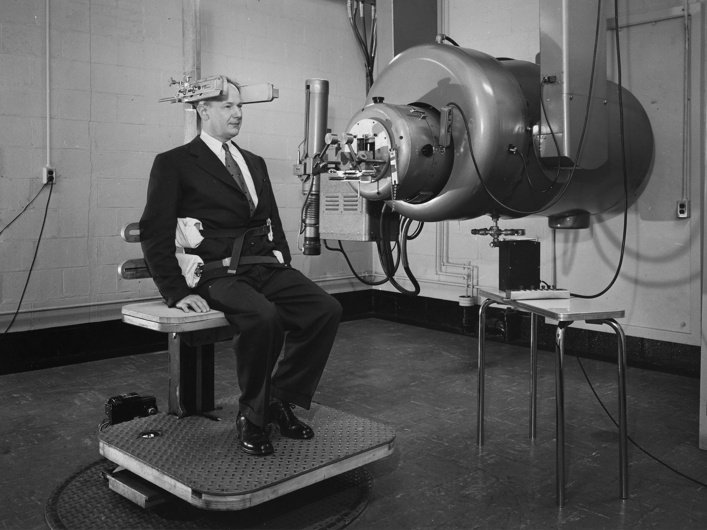 Man sitting in a chair with a large machine next to him.