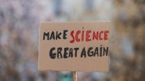 A cardboard sign, with clunky handwritten letters, reading "Make Science Great Again." Science is in red. The rest is in black.