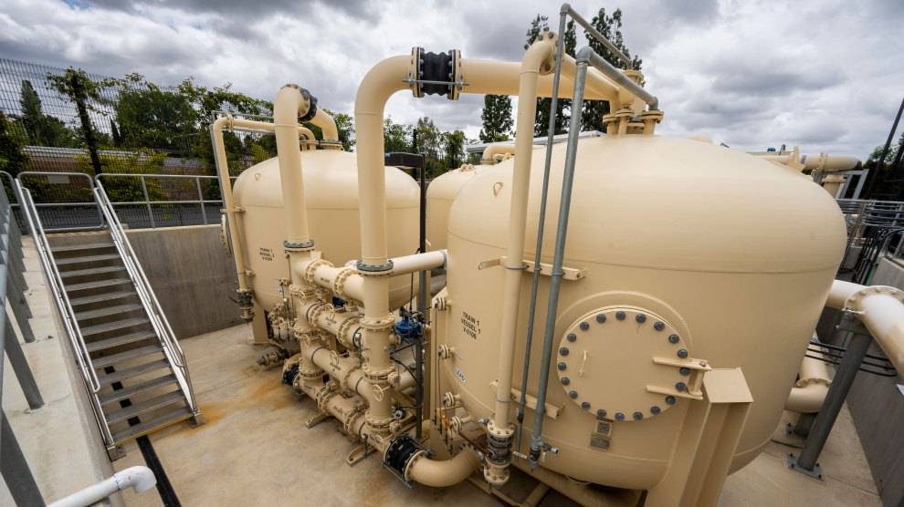 Two large off white tanks in a rectangular cement pit, with pipes running out of them.