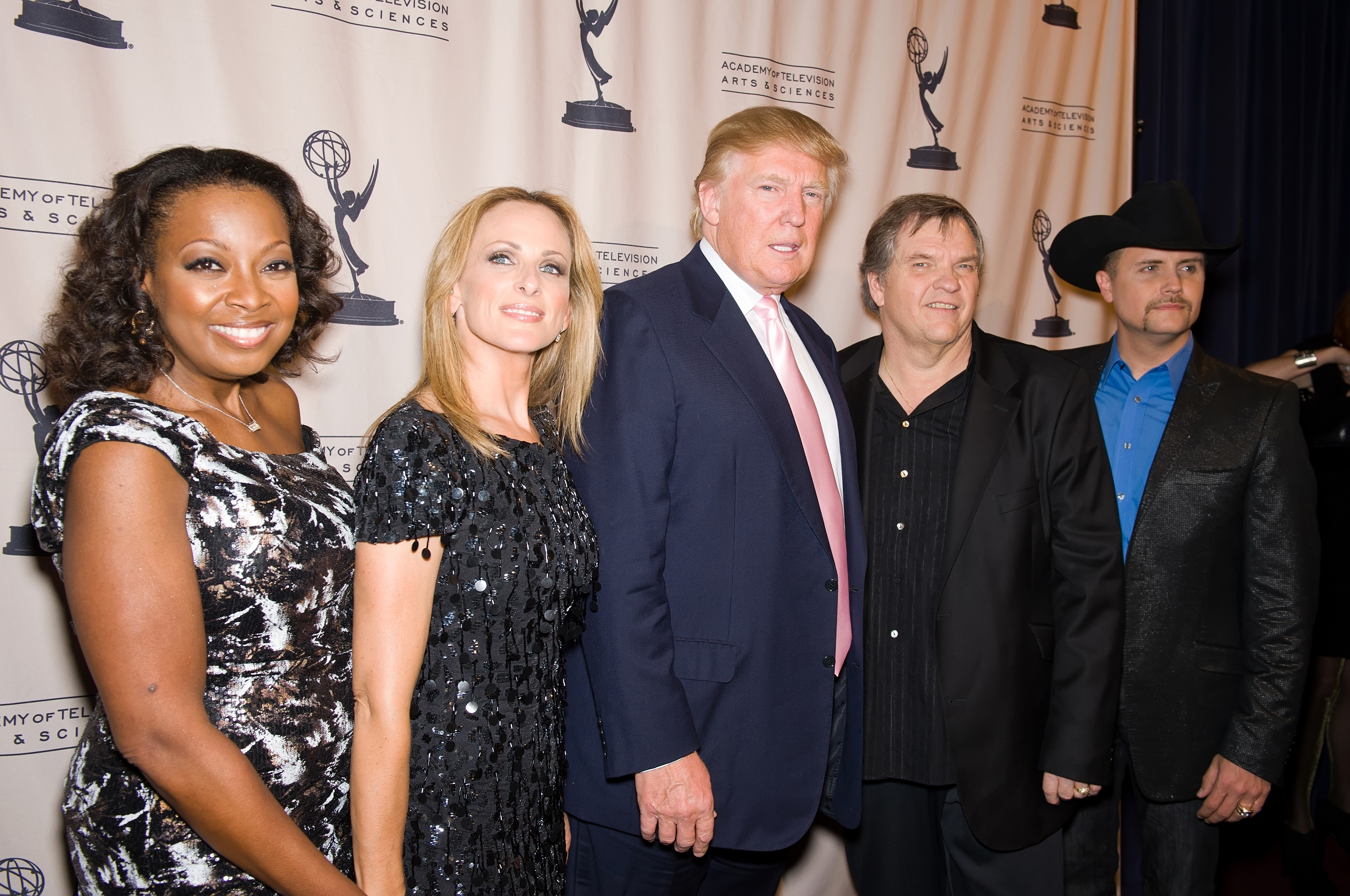 Donald Trump standing, flanked by two people on each side.
