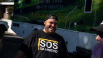 Man with backwards baseball smiling, wearing shirt that reads "SOS Richmond."