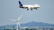A plane flying over a wind turbine.
