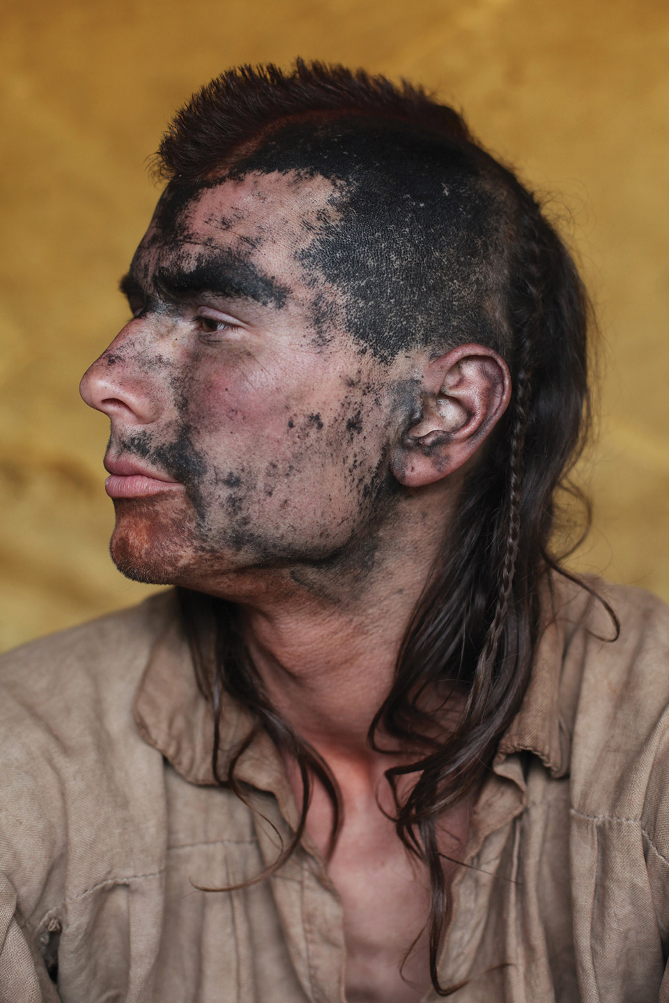 Man dressed as Native American with mohawk and braid.