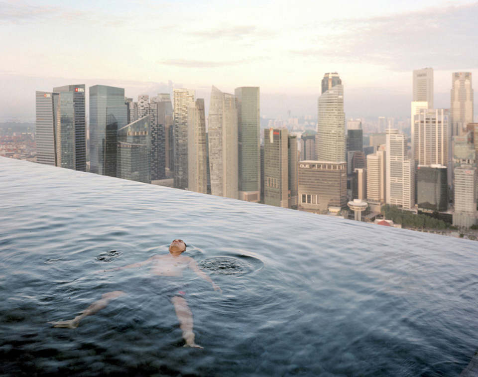 A man floats in the 57th-floor swimming pool of the Marina Bay Sands Hotel, with the skyline of the Singapore financial district behind him.