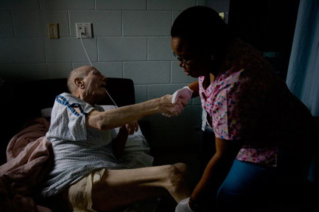 A prison nurse helps Charles Webb, then 74, into bed.